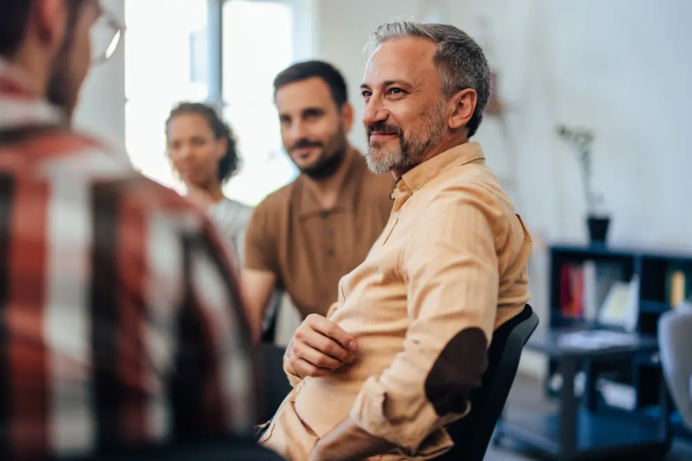 A mature man carefully listened while others spoke during the group therapy.