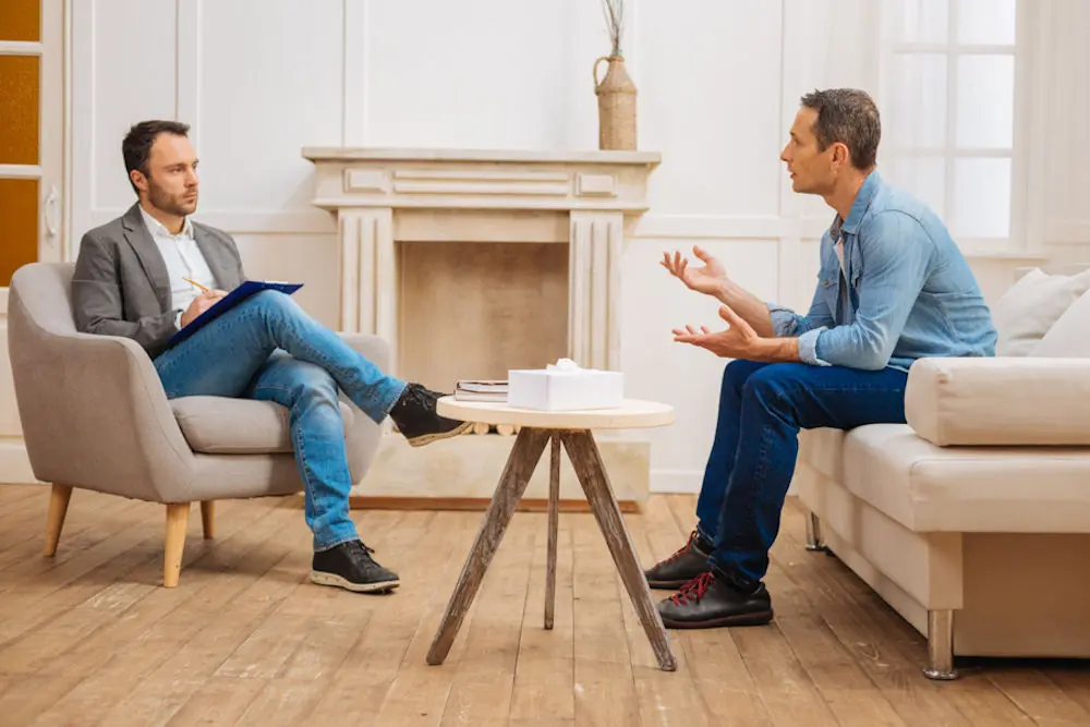 Young man speaks to therapist CBT treatment.