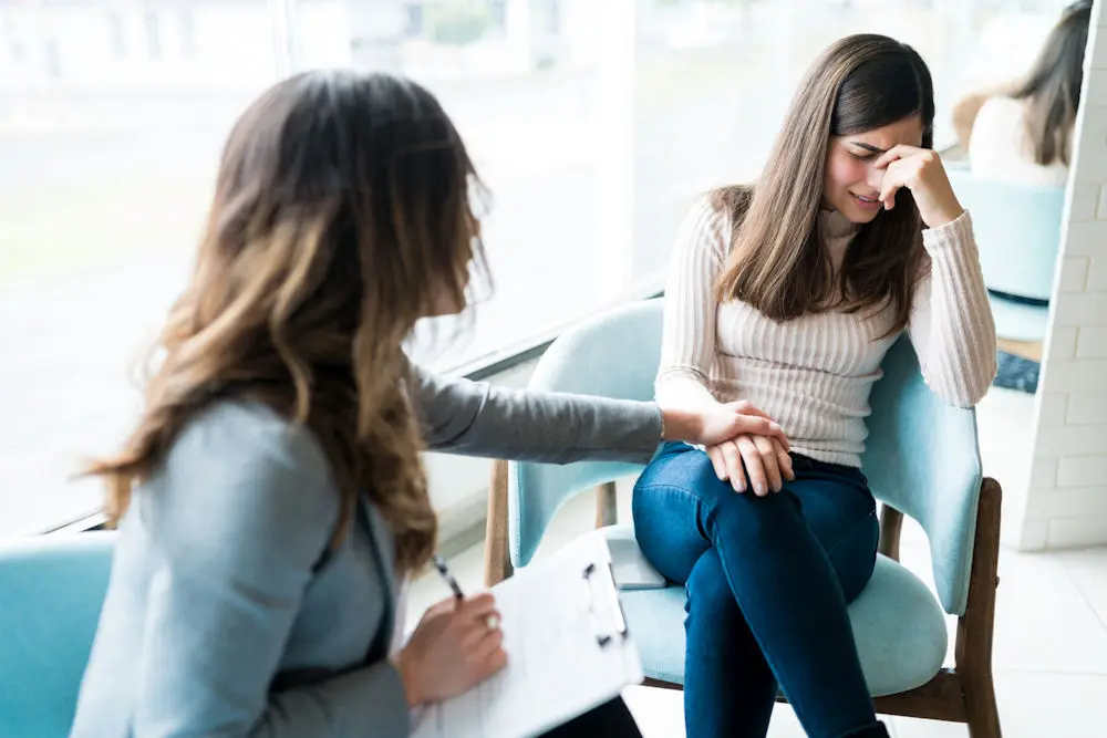 Woman looks to the side with sadness during cognitive behavioral therapy.