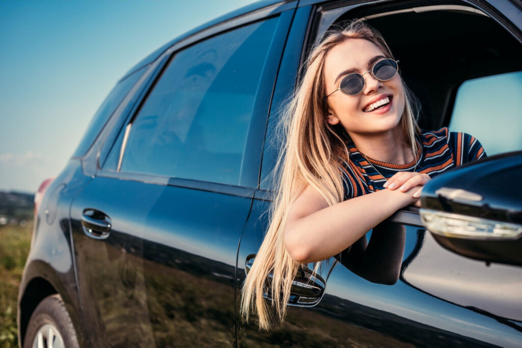 Smiling woman practicing positive self talk while being a passenger in a car